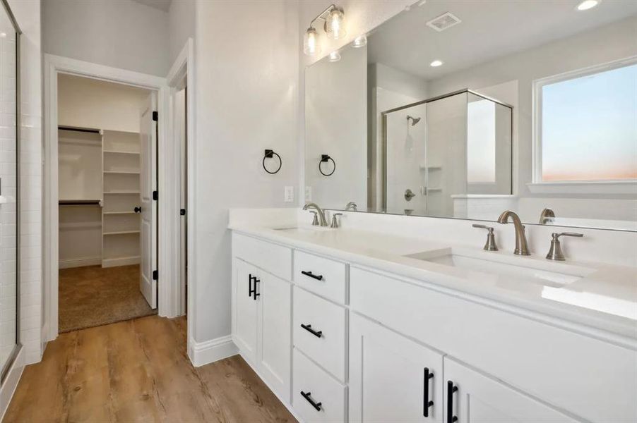 Bathroom featuring vanity, hardwood / wood-style floors, and a shower with shower door