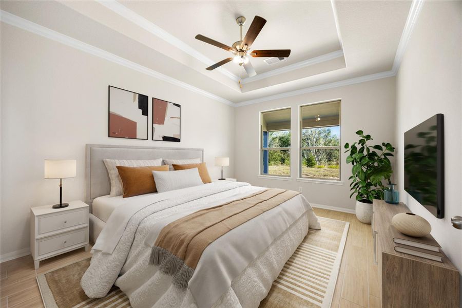 The first-floor primary bedroom is a peaceful retreat, featuring an elegant tray ceiling with a modern ceiling fan and continuous light wood flooring. The space is brightly illuminated by two large windows that offer scenic outdoor views. *Virtually Staged The first-floor primary bedroom is a peaceful retreat, featuring an elegant tray ceiling with a modern ceiling fan and continuous light wood flooring. The space is brightly illuminated by two large windows that offer scenic outdoor views. *Virtually Staged