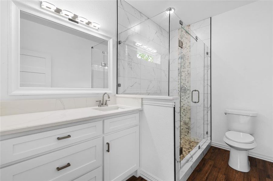 Full bathroom with a marble finish shower, vanity, and dark wood finished floors Full bathroom with a marble finish shower, vanity, and dark wood finished floors