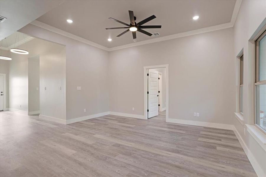 Empty room featuring light hardwood / wood-style floors, crown molding, and ceiling fan