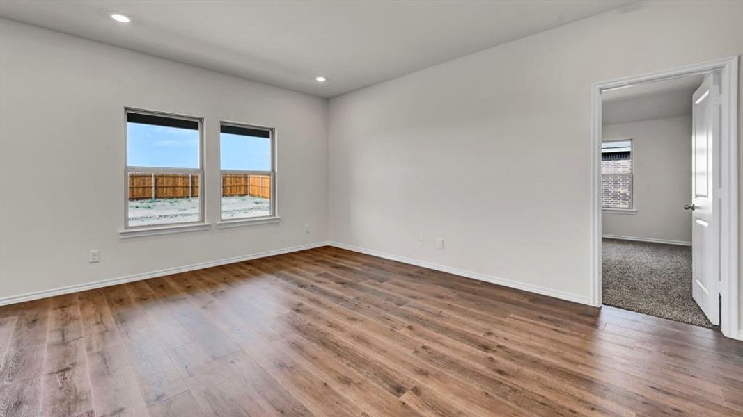 Spacious room featuring wood-finish flooring, recessed lighting, and white baseboards