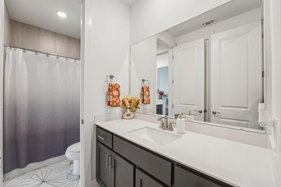 Quartz countertops and sleek cabinetry provide both style and functionality in the guest bathrooms.