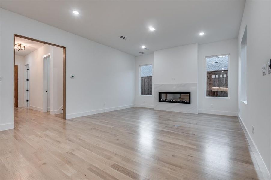 Unfurnished living room with light wood finished floors, a fireplace, and recessed lighting