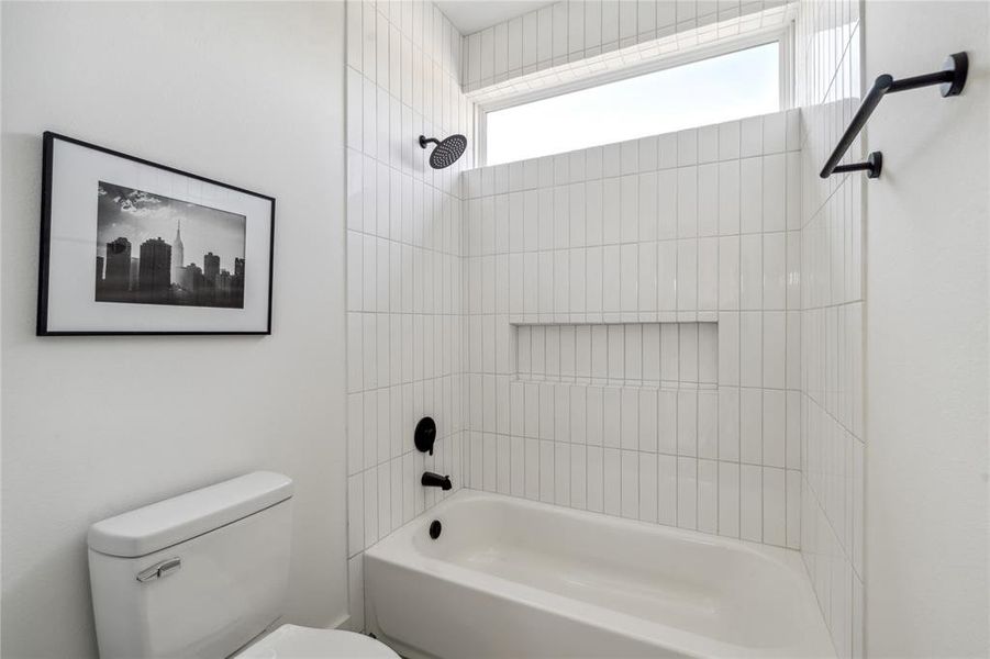 Contemporary bathroom with sleek white subway tile, a built-in shower niche, modern black fixtures, and a clerestory window for natural light and privacy.