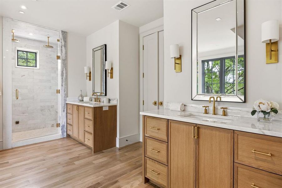 Dual vanity bathroom featuring light wood-finish cabinetry with gold-tone hardware Dual vanity bathroom featuring light wood-finish cabinetry with gold-tone hardware