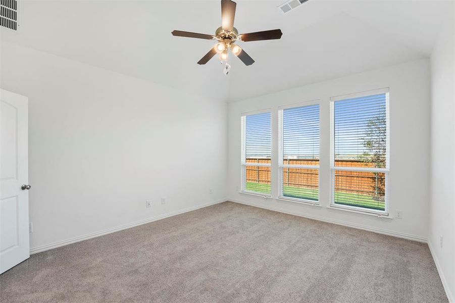 Unfurnished room featuring ceiling fan, vaulted ceiling, and light colored carpet