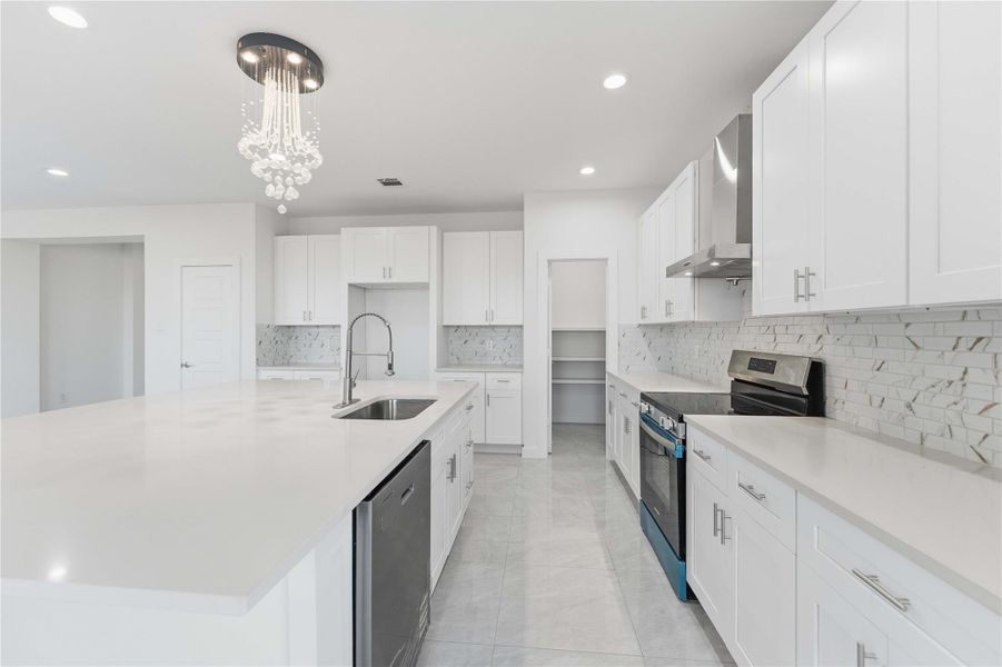 Bright, open kitchen with oversized island and sleek quartz countertops.Custom white cabinetry, stainless appliances, and designer backsplash elevate the space.Elegant pendant lighting and glossy tile floors create a modern, airy feel.