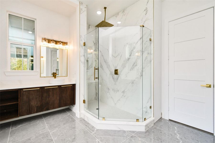 The primary bath features a stunning walk-in shower with floor-to-ceiling marble-patterned tile and premium gold-toned rain shower hardware.