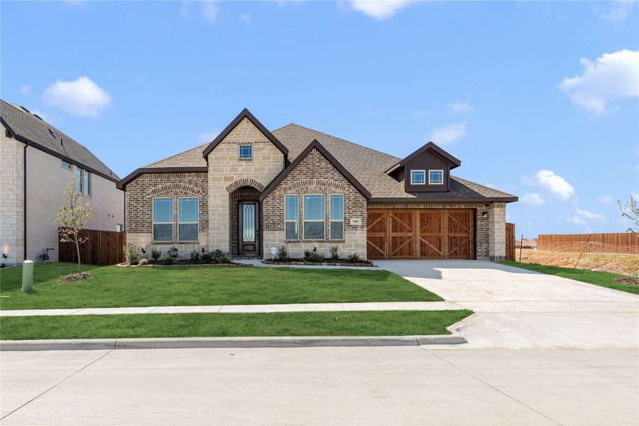 Single-story home with brick and stone exterior, wood garage doors, and manicured front lawn Single-story home with brick and stone exterior, wood garage doors, and manicured front lawn