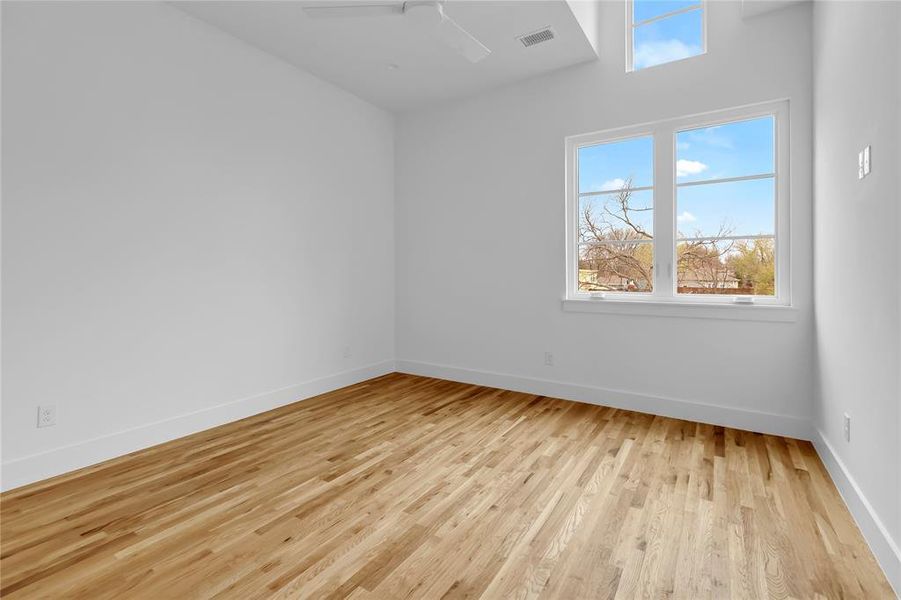 Empty room with light wood finished floors and a ceiling fan
