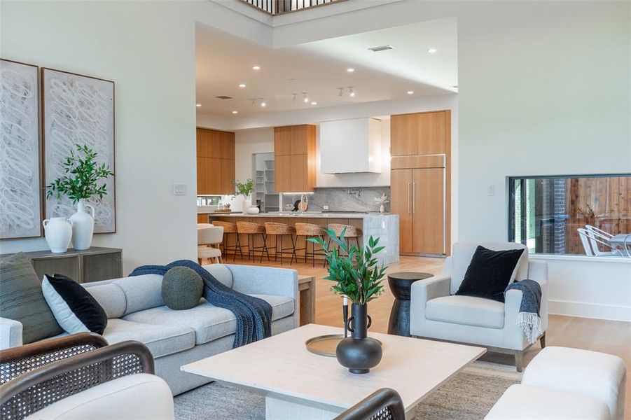 Open-concept living space featuring wood-finish flooring, a contemporary fireplace with a horizontal window, and recessed lighting