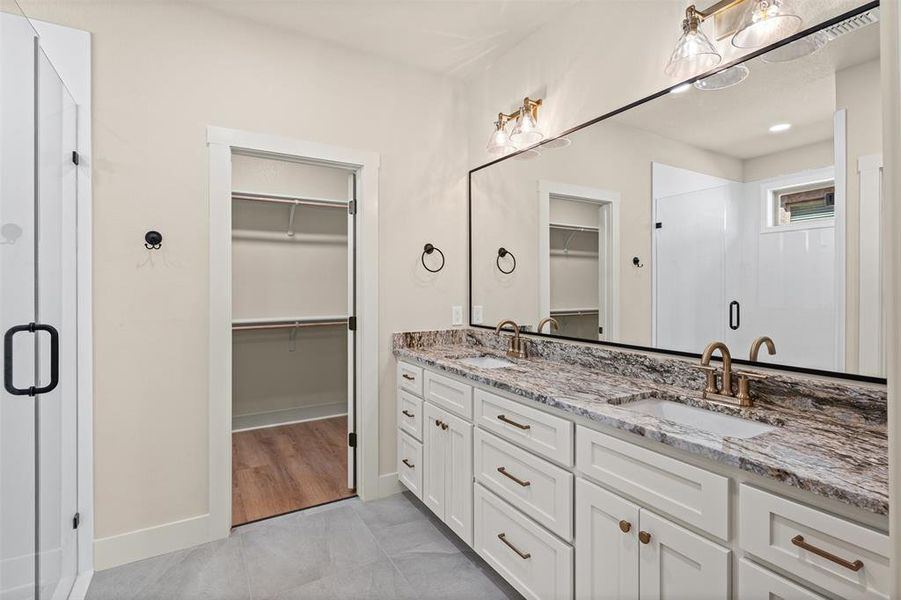 Bathroom with a spacious closet, a stall shower, and double vanity