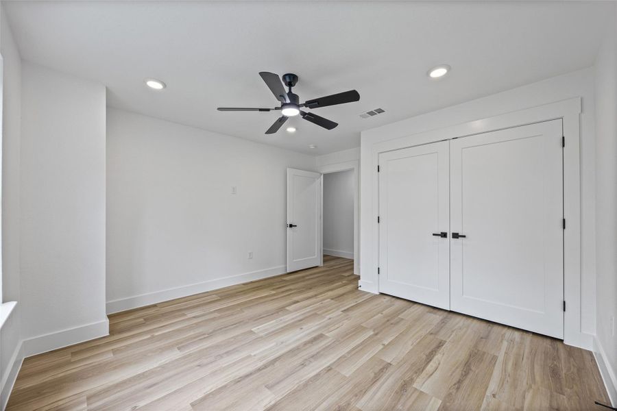 Spacious bedroom featuring wood-finish flooring, recessed lighting, and a modern ceiling fan Spacious bedroom featuring wood-finish flooring, recessed lighting, and a modern ceiling fan