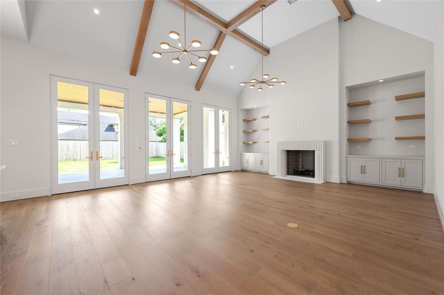 Vaulted ceilings and a second fireplace with custom shelving and cabinets are highlights of the living room.  This large open space with multiple doors to the outdoor patio allows for ample entertaining space in the home.