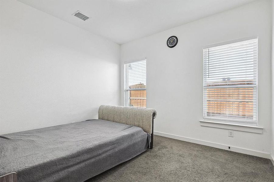 Bedroom with multiple windows and carpet