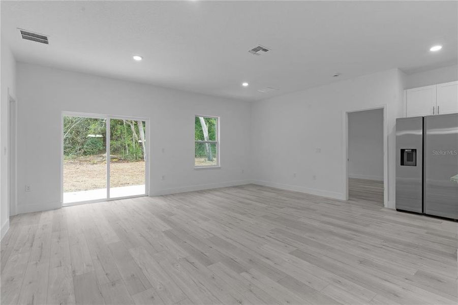 From dining area across living room. The door beside the refrigerator leads into primary suite.