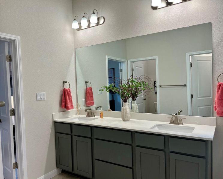Full bathroom featuring double vanity and a textured wall Full bathroom featuring double vanity and a textured wall