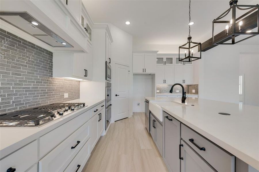 Kitchen featuring white cabinetry, pendant lighting, sink, appliances with stainless steel finishes, and backsplash