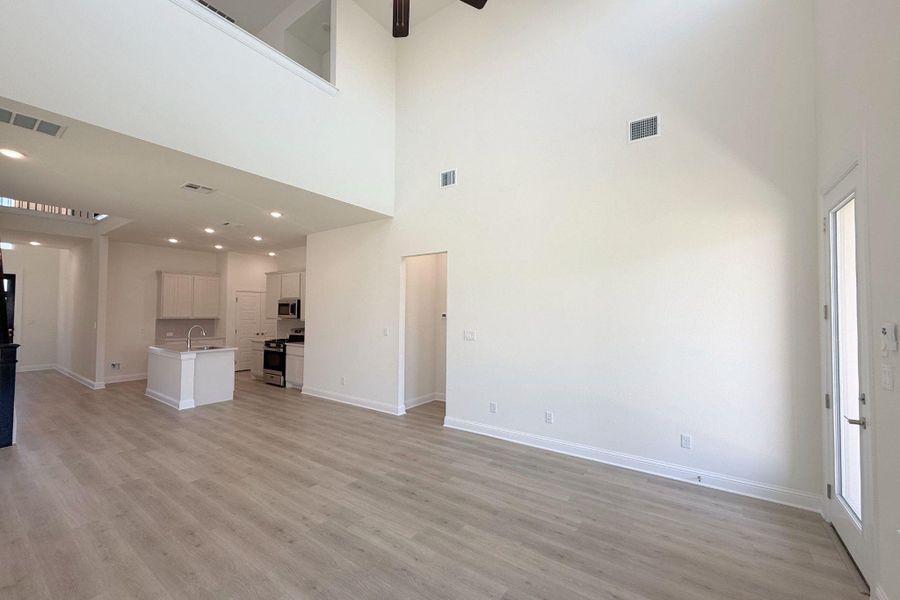Open-concept living area featuring a vaulted ceiling and light wood-finish flooring Open-concept living area featuring a vaulted ceiling and light wood-finish flooring
