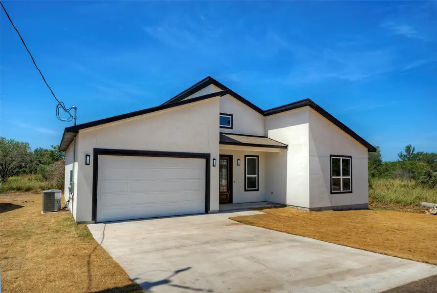 Crisp stucco walls and a clean concrete driveway define this modern single-story exterior. Crisp stucco walls and a clean concrete driveway define this modern single-story exterior.