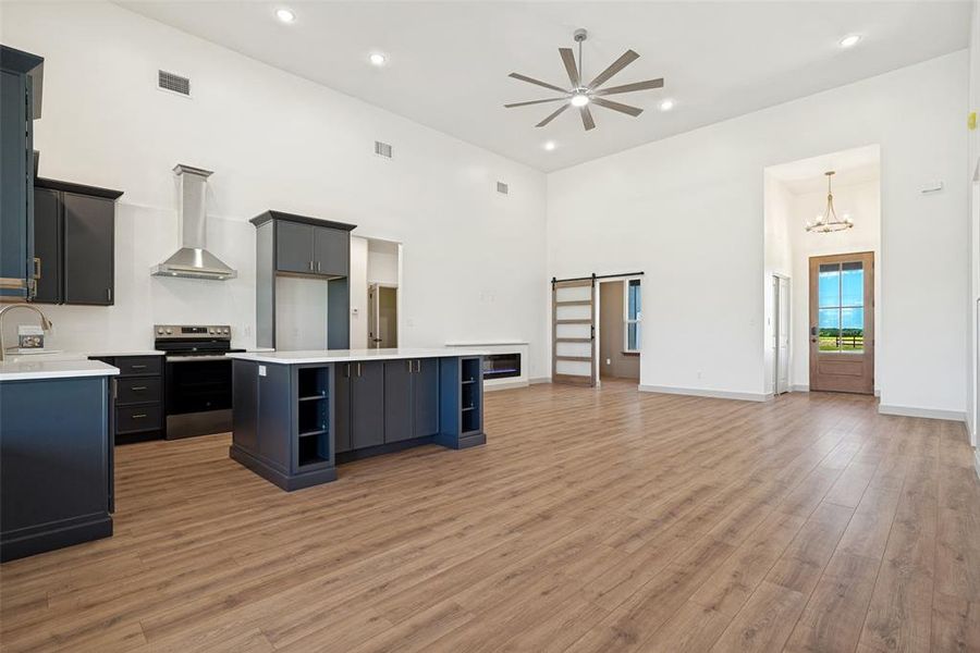 Expansive open-concept living area featuring high vaulted ceilings, recessed lighting, and wood-finish flooring