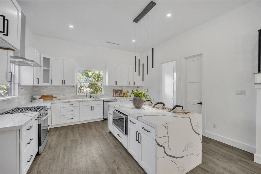 Kitchen featuring white cabinetry, stainless steel appliances, a kitchen island, and a healthy amount of sunlight