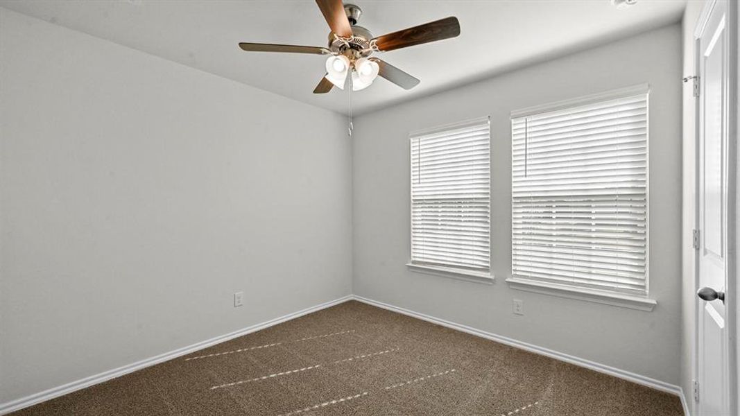 Spare room featuring dark colored carpet and ceiling fan