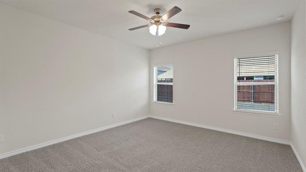 Carpeted empty room with baseboards and a ceiling fan Carpeted empty room with baseboards and a ceiling fan