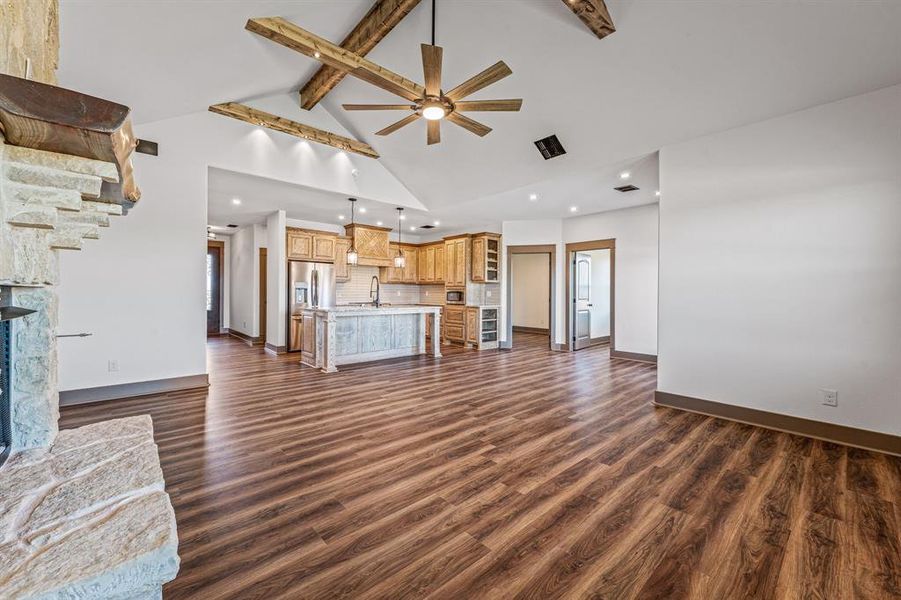 Unfurnished living room featuring beamed ceiling, dark wood finished floors, high vaulted ceiling, a ceiling fan, and recessed lighting