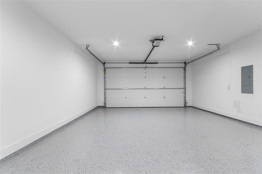 Garage featuring an automatic overhead door, recessed lighting, and a durable speckled epoxy floor finish Garage featuring an automatic overhead door, recessed lighting, and a durable speckled epoxy floor finish