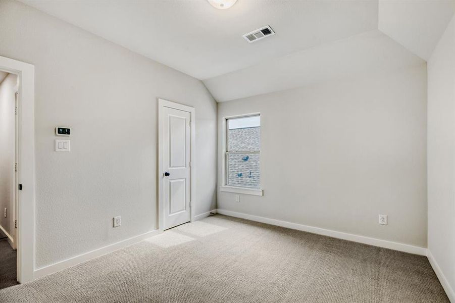 Unfurnished bedroom with vaulted ceiling and carpet
