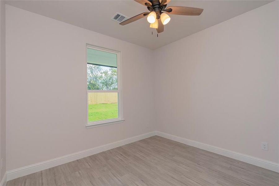 Empty room with ceiling fan and light wood-type flooring