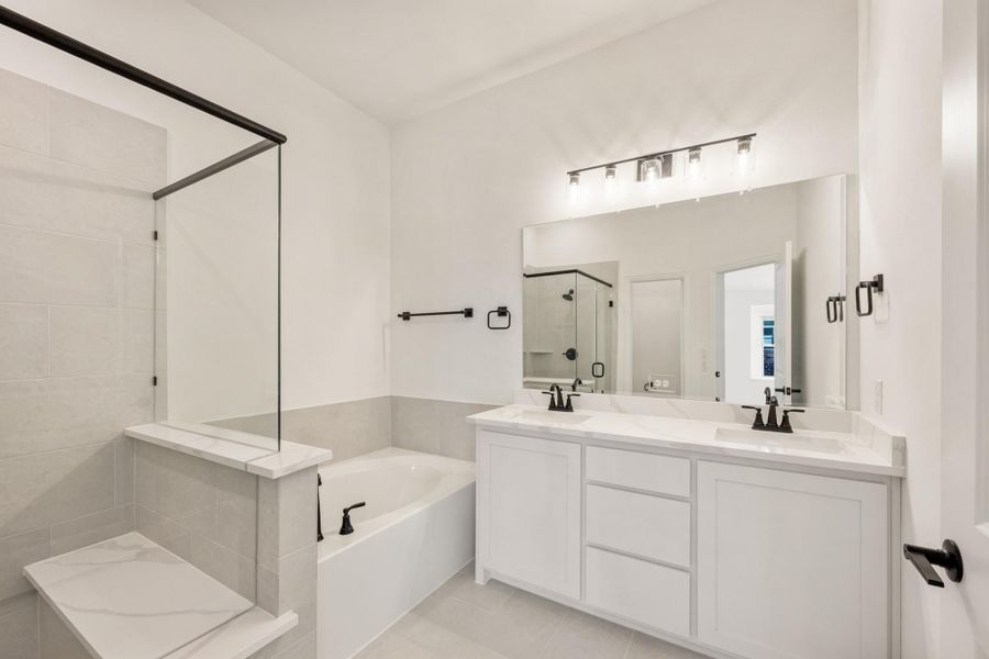 Bathroom with double vanity, soaking tub, and glass shower featuring white cabinets and black fixtures