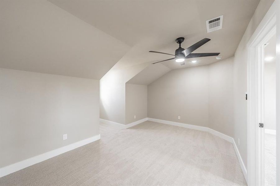 Additional living space featuring light colored carpet, vaulted ceiling, and ceiling fan Additional living space featuring light colored carpet, vaulted ceiling, and ceiling fan