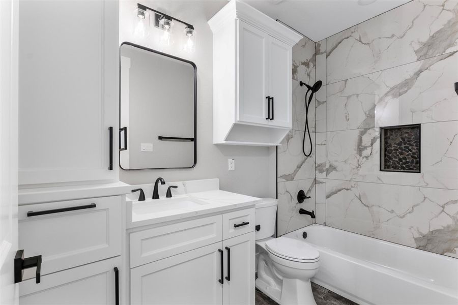 Elegant bathroom featuring a sleek white vanity with modern fixtures, contrasted by a marble-tiled shower and tub combo.