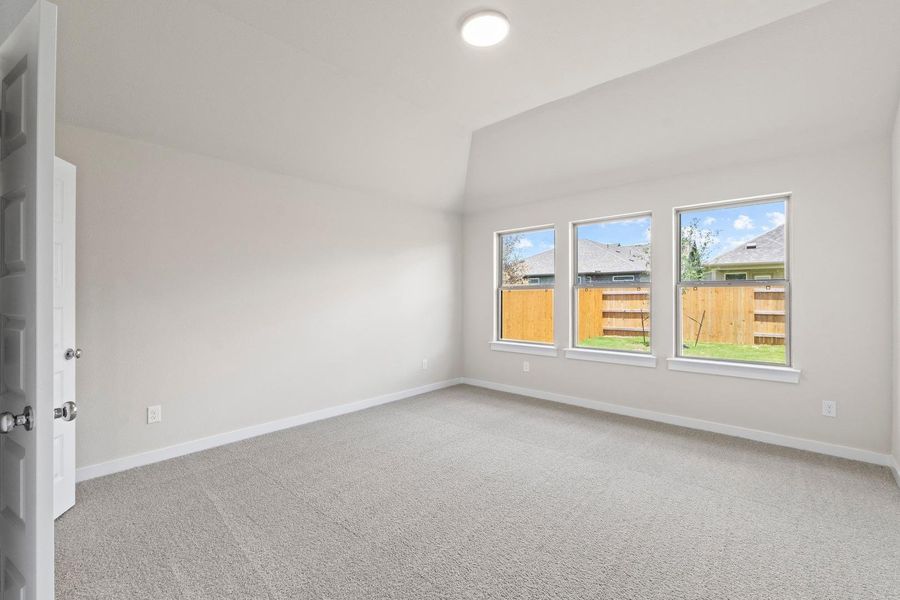 A well-lit bedroom features plush carpet and multiple windows offering views of the private yard.