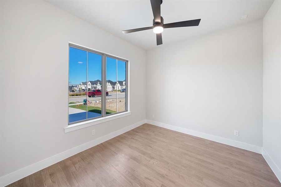 Empty room featuring light wood finished floors, a residential view, and a ceiling fan Empty room featuring light wood finished floors, a residential view, and a ceiling fan
