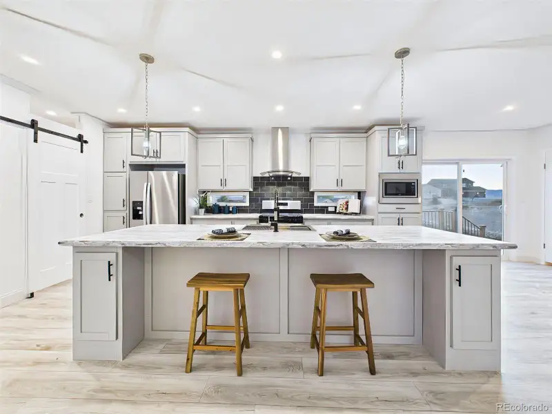 Spacious gourmet kitchen featuring a large center island, stainless steel appliances, and sleek pendant lighting. Spacious gourmet kitchen featuring a large center island, stainless steel appliances, and sleek pendant lighting.