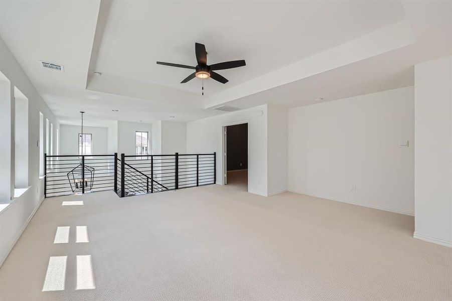 Carpeted empty room featuring a raised ceiling and ceiling fan