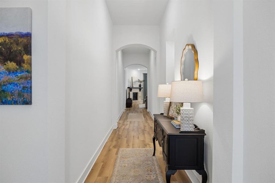 Hallway featuring wood-finish flooring, light neutral wall tones, and an arched entry