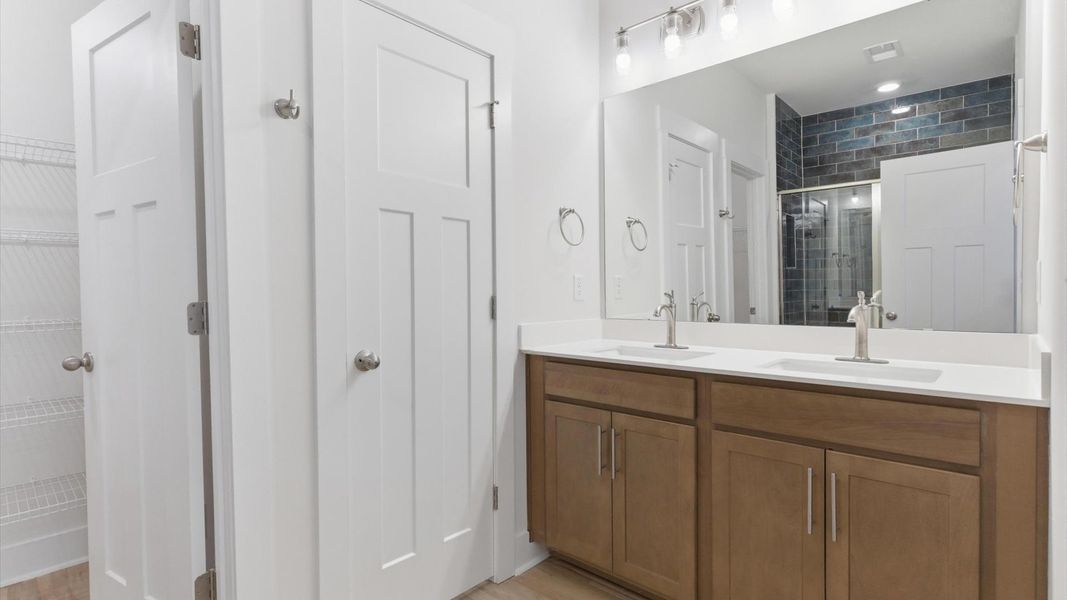 Highly functional and elegant en-suite with dual vanities, tiled walk-in shower, and refined finishes