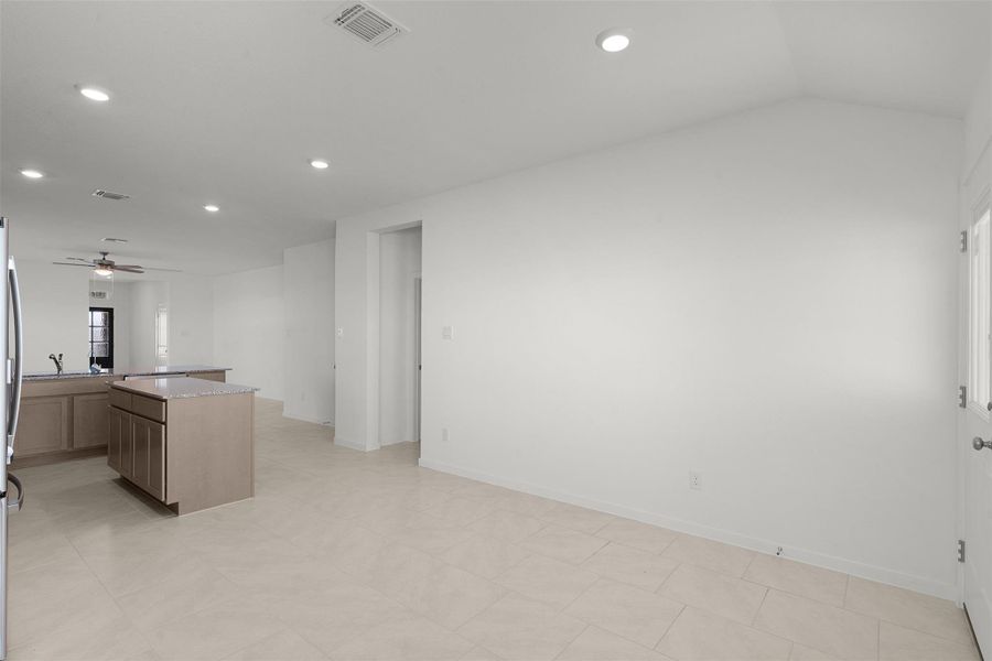 Kitchen with a kitchen island, ceiling fan, recessed lighting, light stone counters, and freestanding refrigerator
