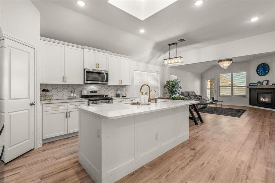 Kitchen with white cabinetry, light hardwood / wood-style flooring, lofted ceiling, and appliances with stainless steel finishes