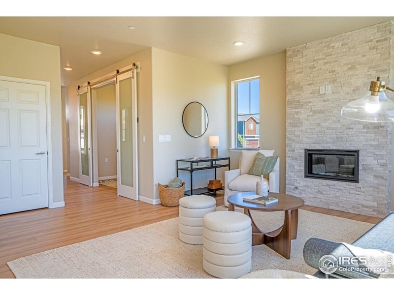 living space with floor to ceiling stacked rock fireplace and office pocket doors