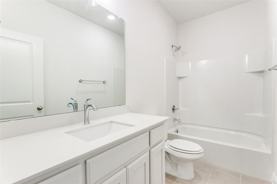 Full bathroom with washtub / shower combination, tile patterned floors, toilet, and vanity