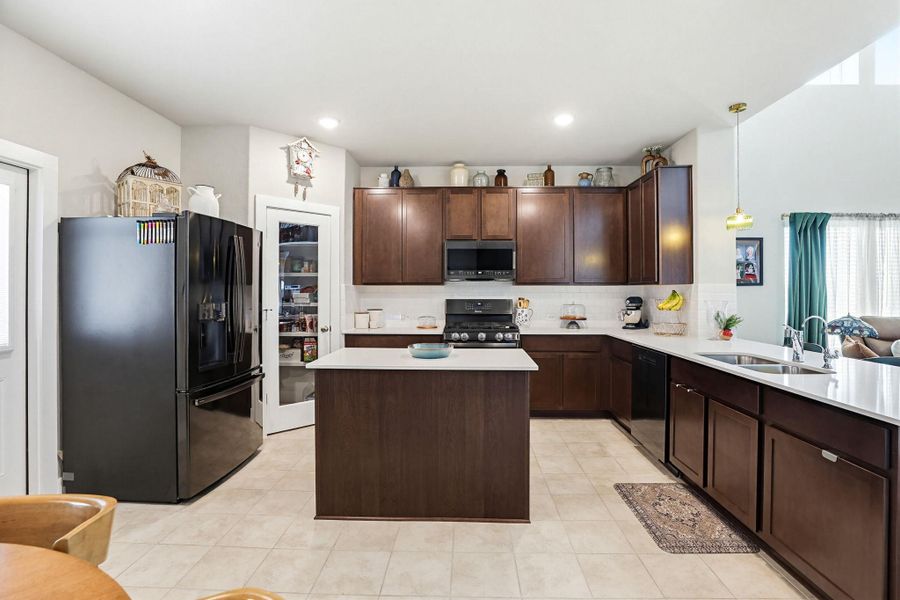 Kitchen featuring dark wood cabinetry, a central island, white countertops, and tile flooring