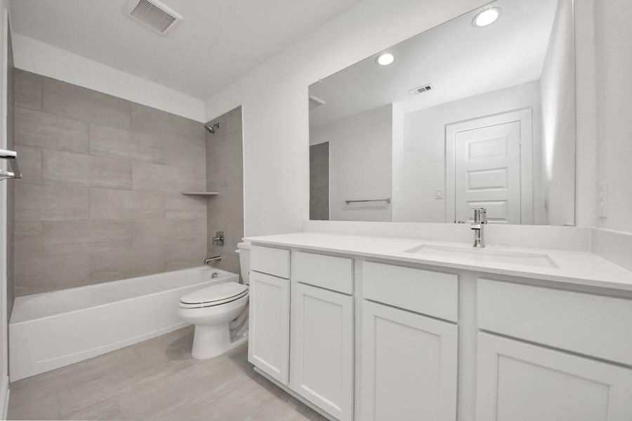 Secondary bath features tile flooring, bath/shower combo with tile surround, light stained wood cabinets, beautiful light countertop. Secondary bath features tile flooring, bath/shower combo with tile surround, light stained wood cabinets, beautiful light countertop.