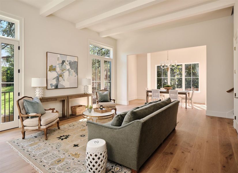 Bright 12ft beamed ceiling living room with abundant windows, transom doors,  and views out on all three sides. Dining room centered by a designer chandelier looks out onto Magnolia trees.