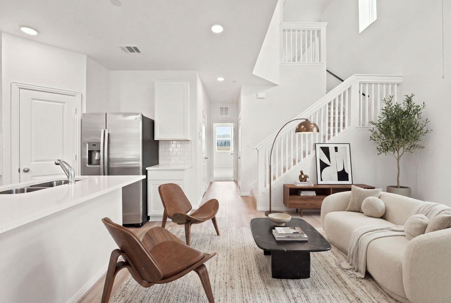 An open main floor joins the living area to the kitchen beside a white staircase.