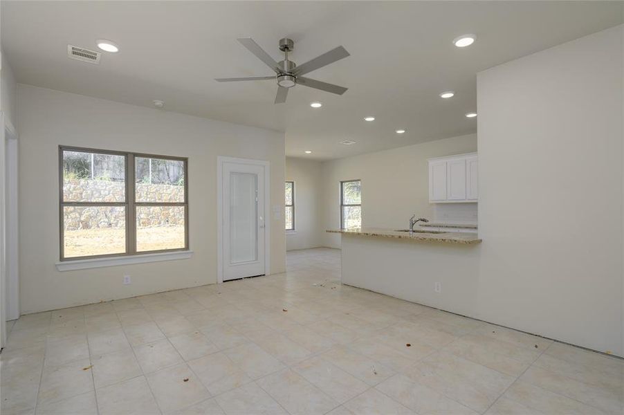 Unfurnished living room featuring ceiling fan and sink